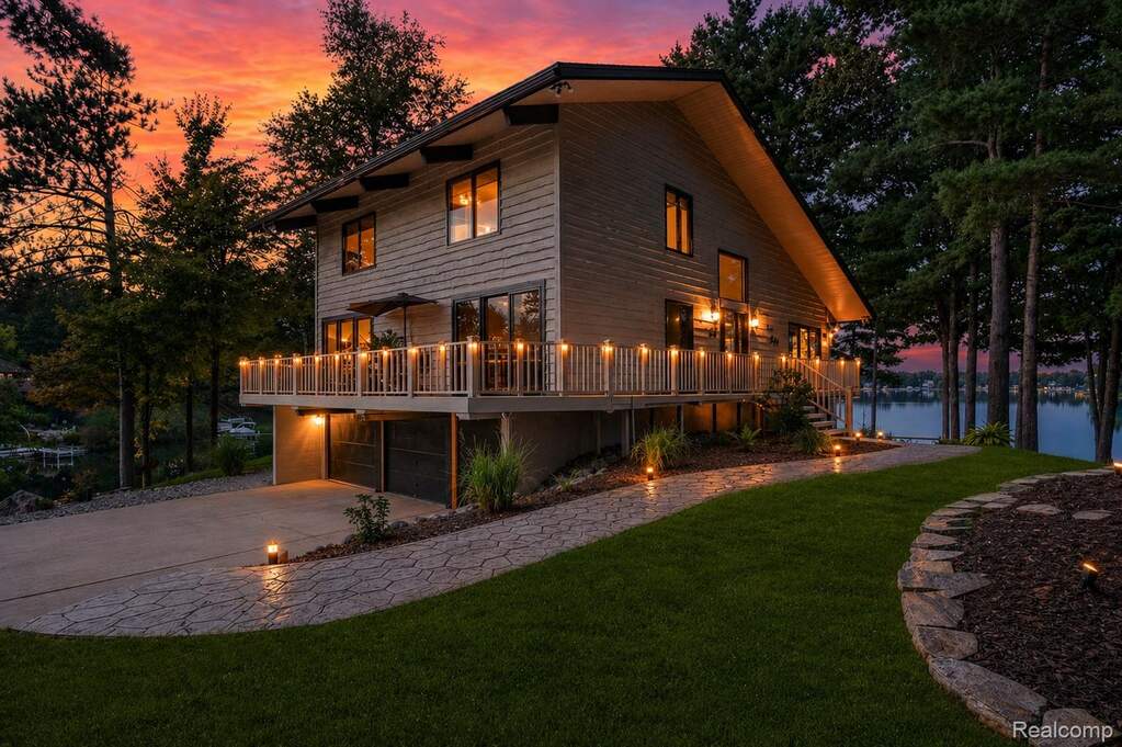 Back of house at dusk featuring a lawn, concrete driveway, a garage, and a deck
