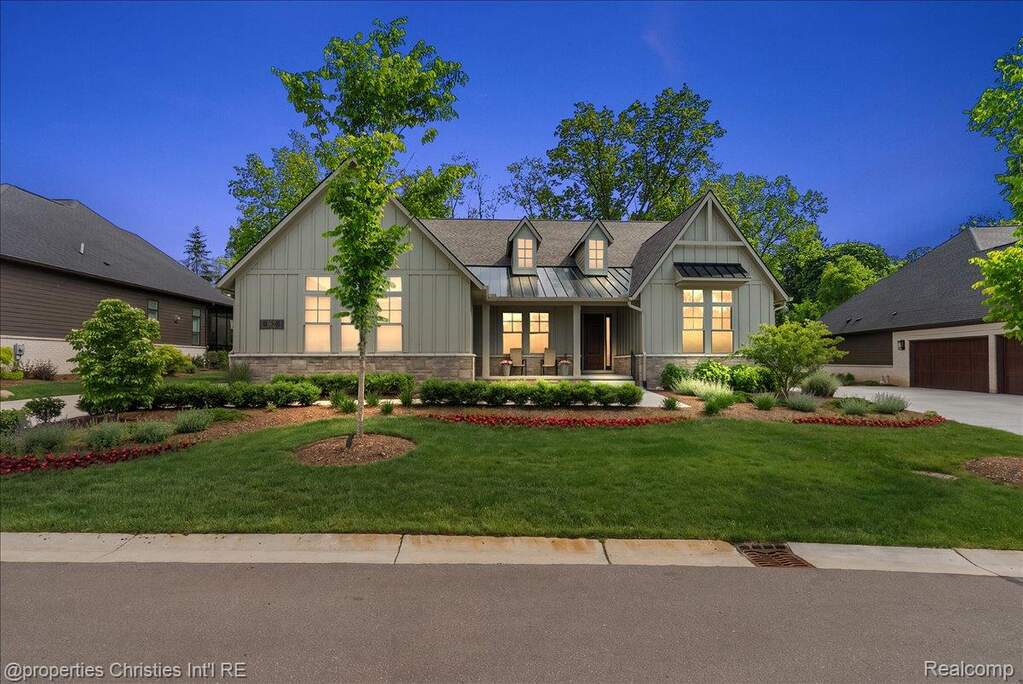 Craftsman-style home featuring board and batten siding, stone facade accents, a metal accent roof, gabled dormers, and a two-car garage