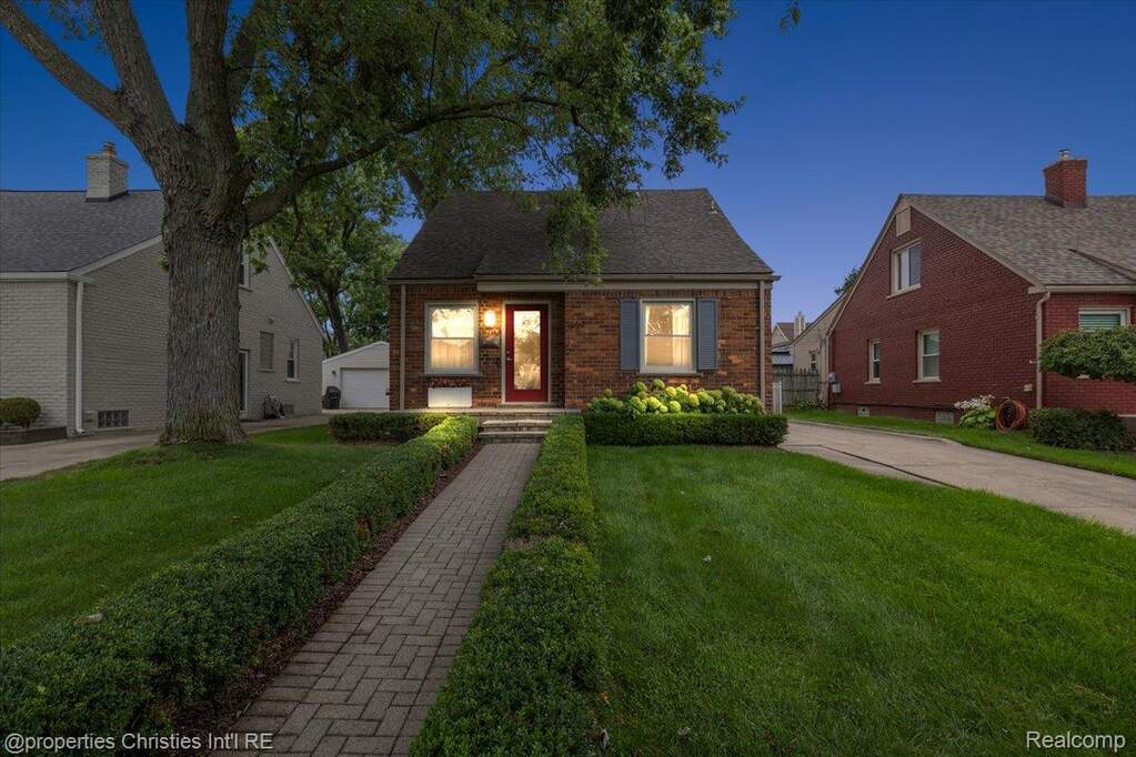 View of front of home with a lawn and brick siding