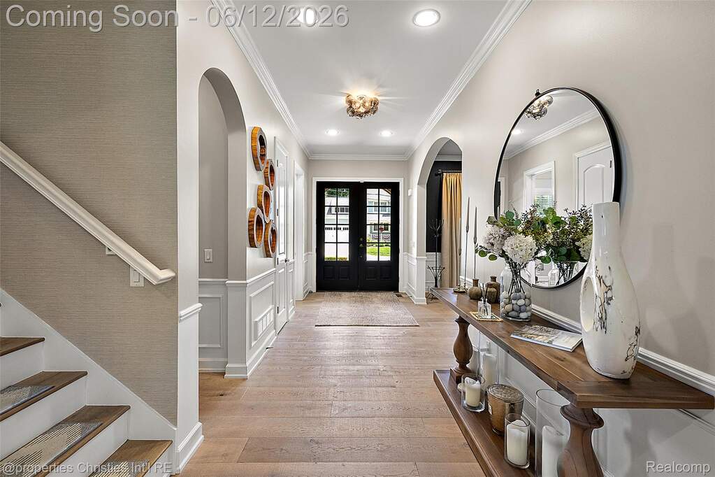 Foyer featuring light wood-finish flooring, wainscoting, arched doorways, a black paneled front door with glass, and recessed lighting