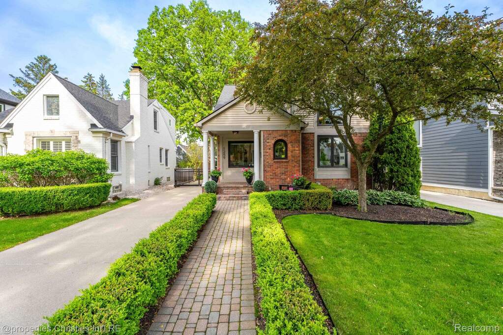View of front of home featuring brick siding, a front lawn, and a porch