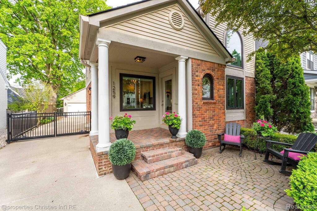 View of exterior entry with brick siding, a porch, and a detached garage