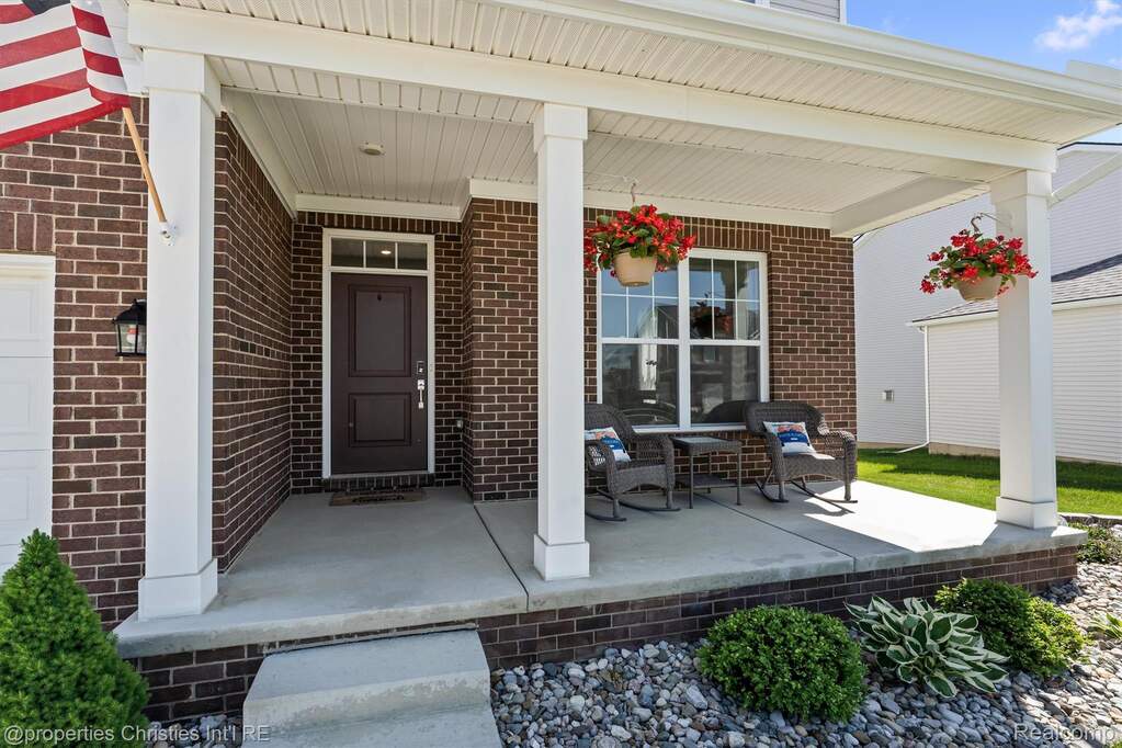 Entrance to property with a porch and brick siding