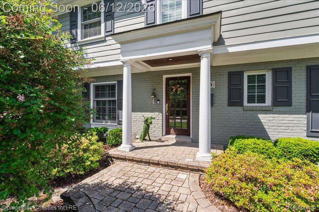 Front entry with a portico featuring two white columns and a paneled wood door with glass inserts