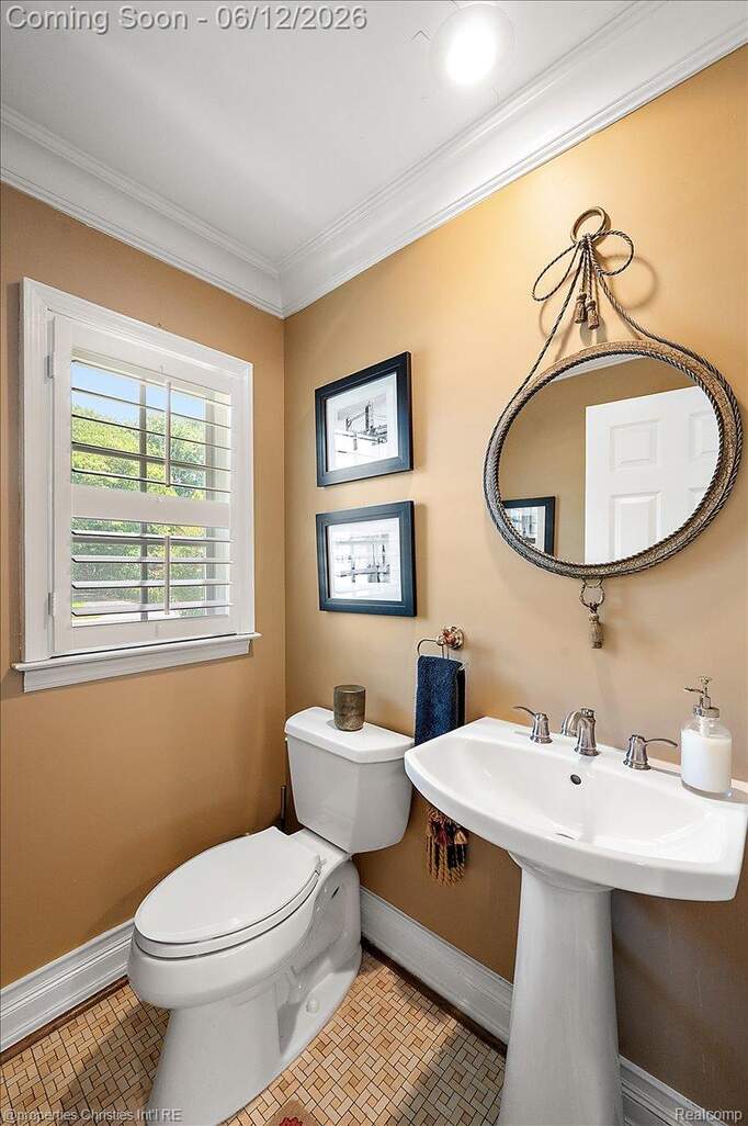 Bathroom featuring a pedestal sink, white toilet, and window with plantation shutters