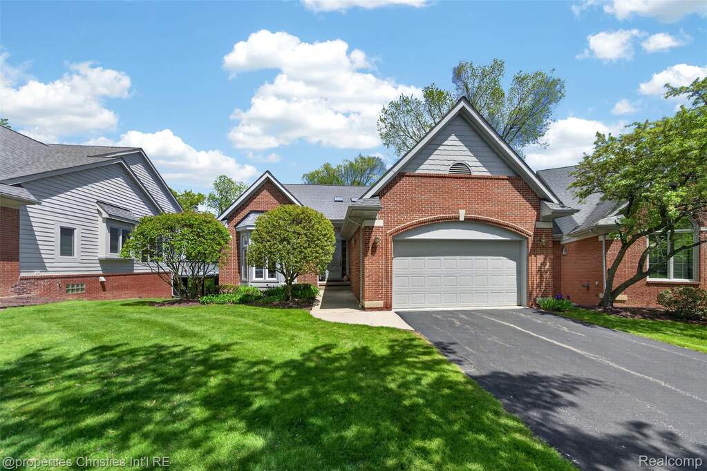 View of front facade with an attached garage, brick siding, asphalt driveway, and a front lawn