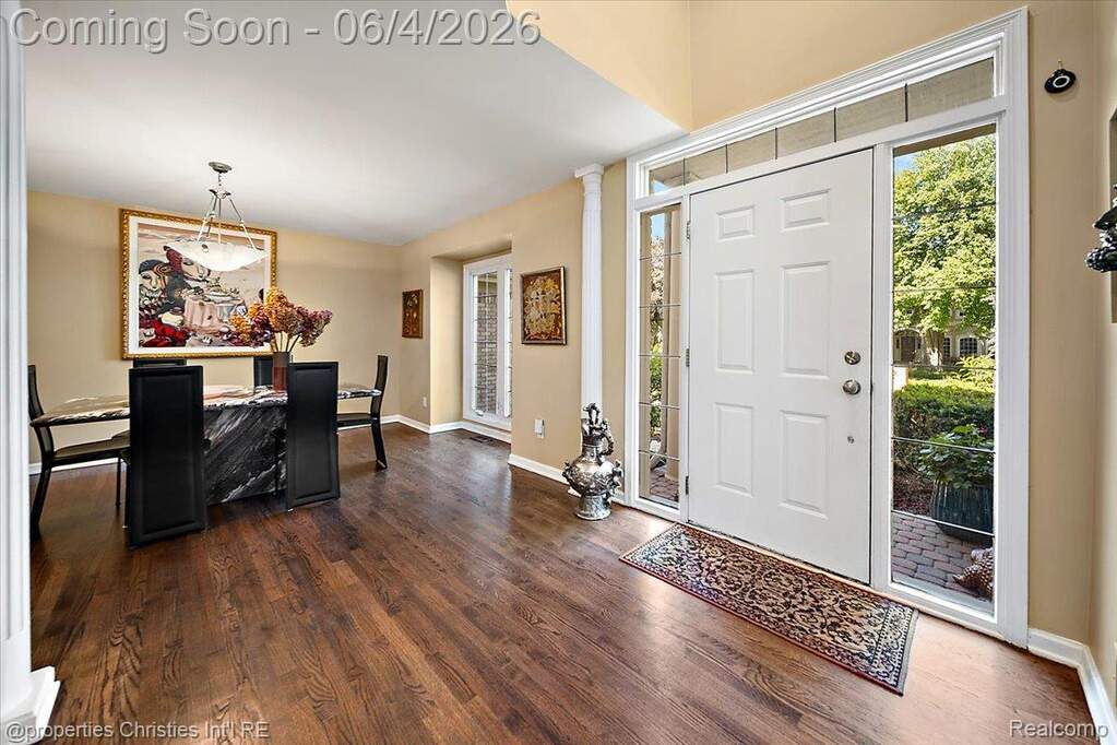 Entry foyer with wood-finish flooring, a white paneled door with sidelights, and a transom window
