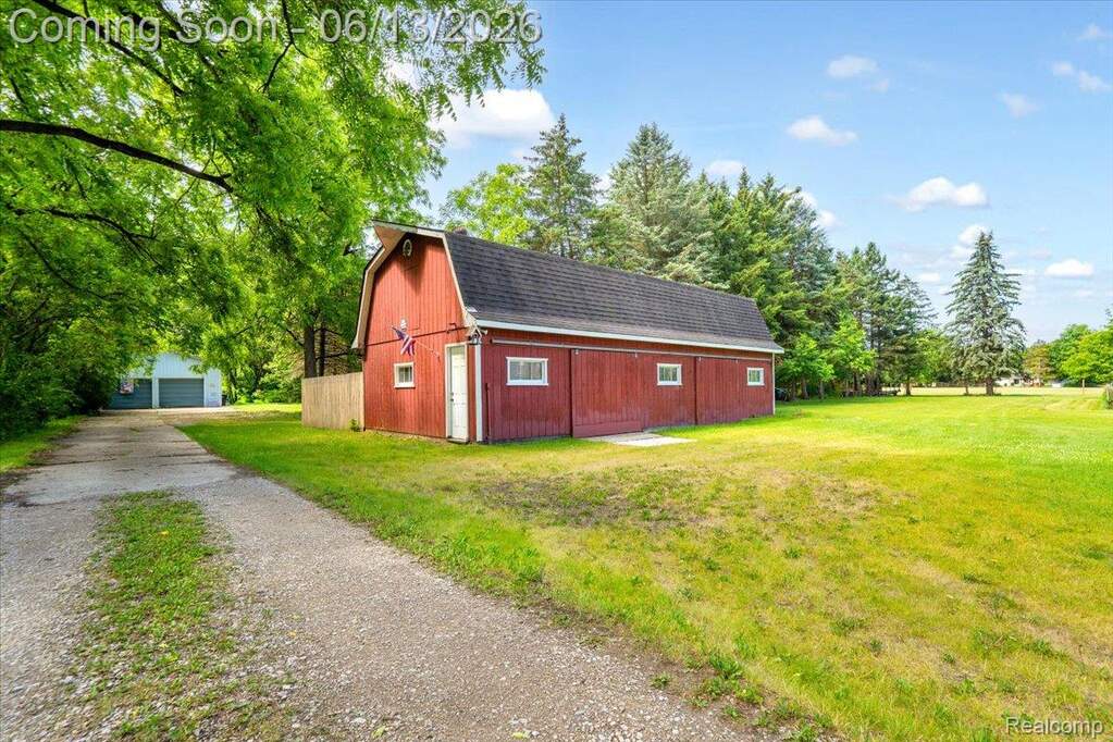 Red-sided barn structure featuring a gambrel roof and multiple windows
