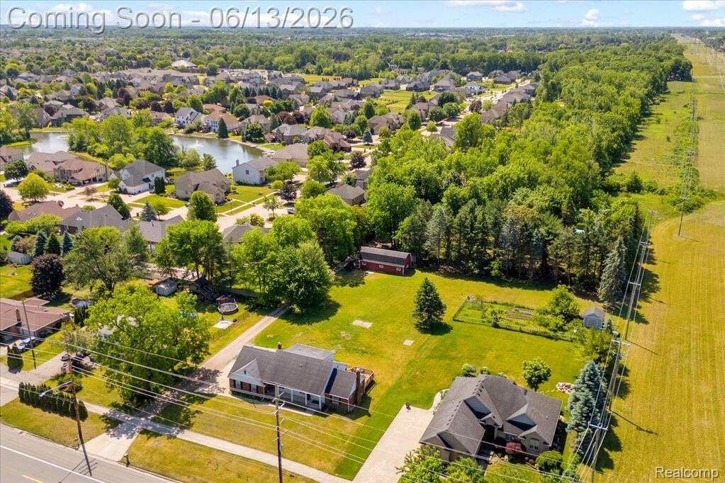 Expansive property featuring a large green lawn, mature trees, and a visible pond within the surrounding residential area