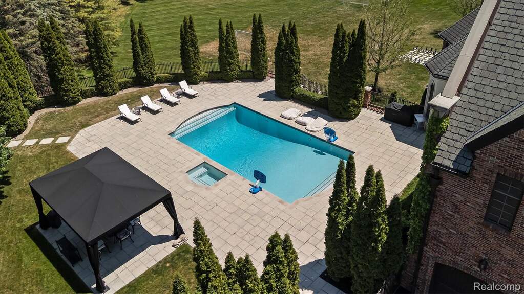 Expansive outdoor living area featuring a rectangular pool with integrated spa