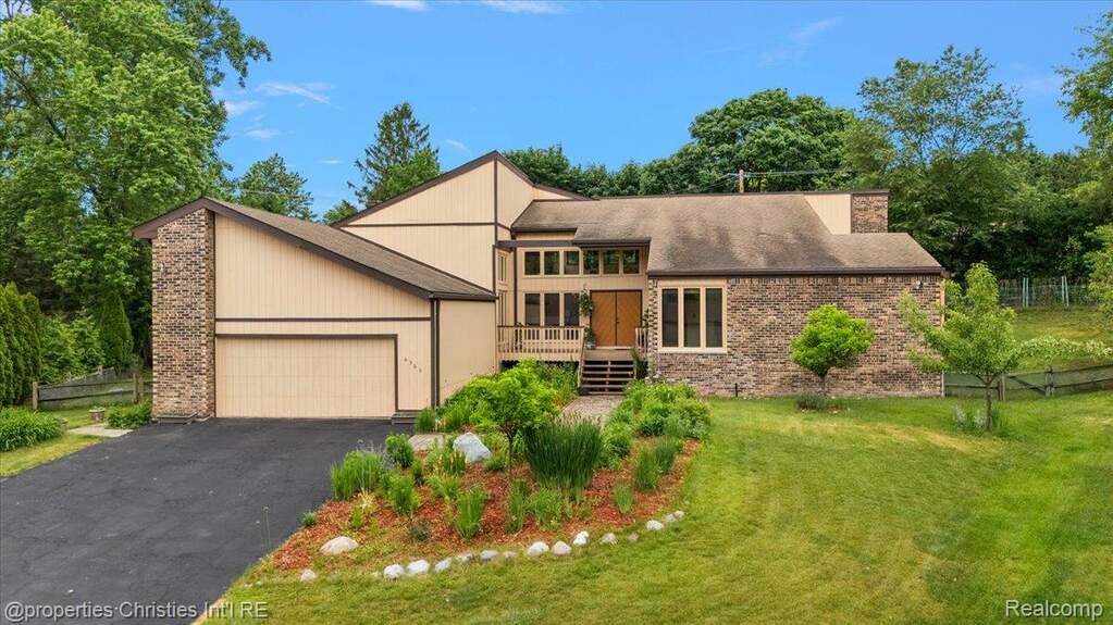 Mid-century home with a front lawn, driveway, a garage, and brick siding