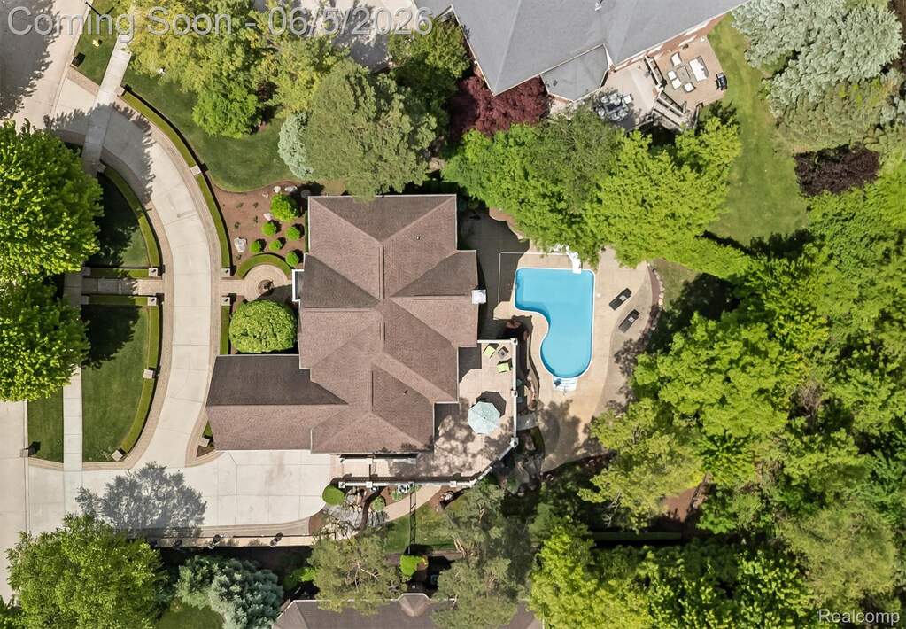 Expansive property featuring a multi-gabled main residence, a large swimming pool, a concrete patio, and a curved driveway