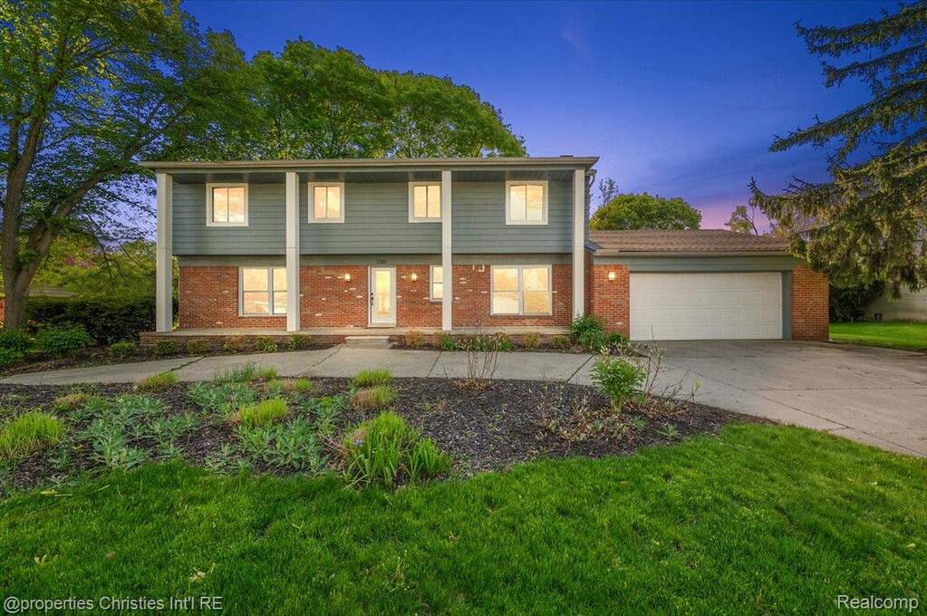 Colonial inspired home with an attached garage, concrete driveway, brick siding, and a front yard