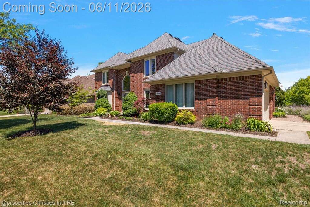 Brick exterior with a gabled roofline, arched window, and landscaped foundation planting