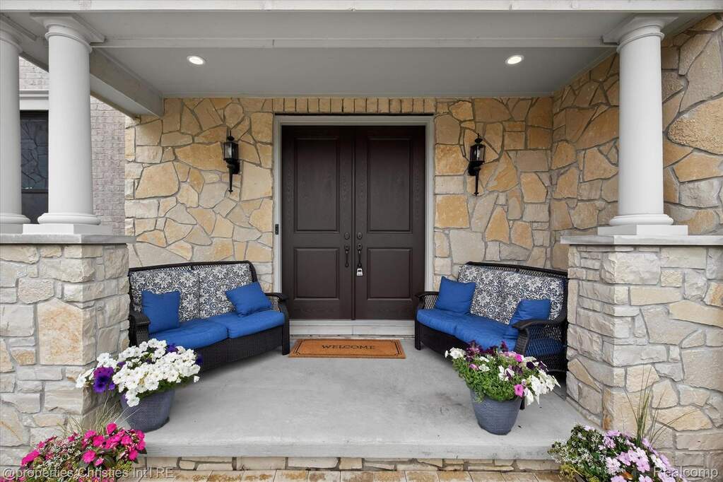 Stone veneer facade featuring a double entry door with paneled design, flanked by two wall sconces