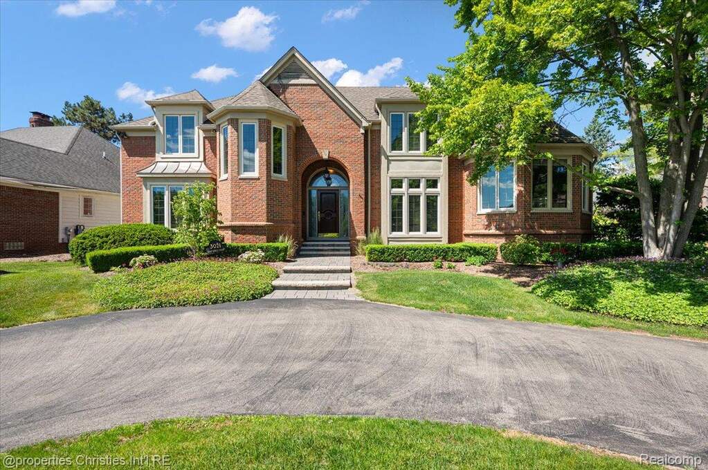 Brick exterior featuring an arched entry, multiple bay windows, stone window sills, and a stone staircase