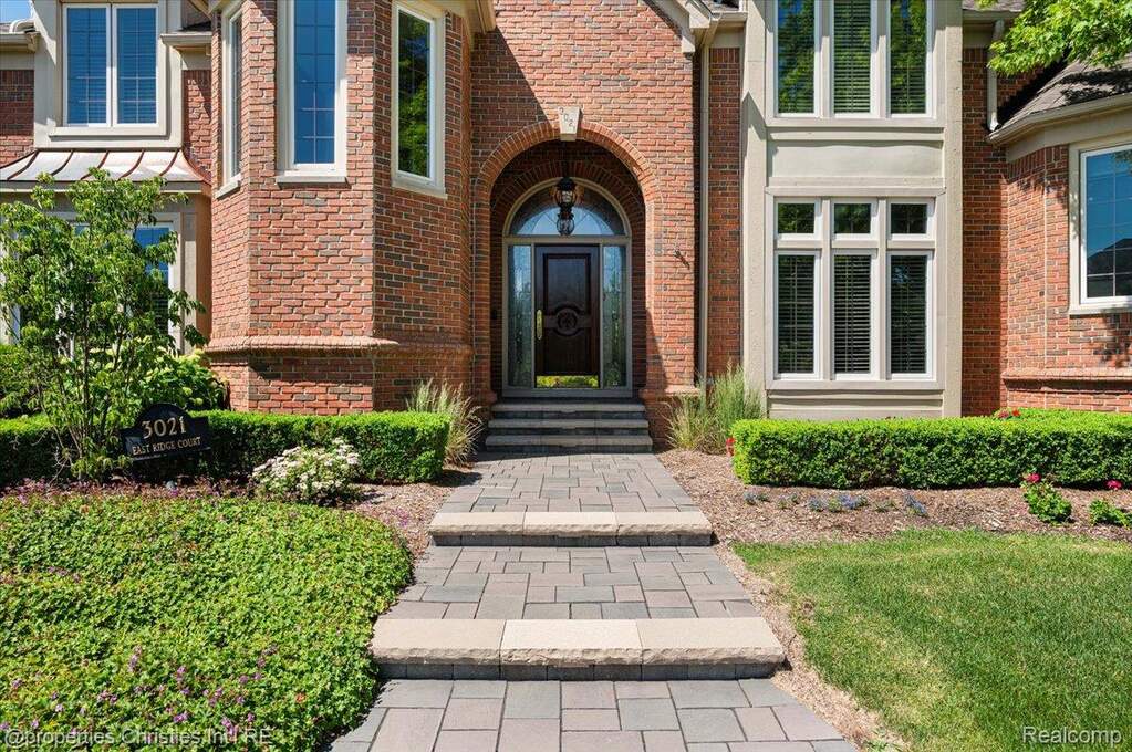 Brick-clad exterior featuring an arched entryway with a dark wood door and glass panels