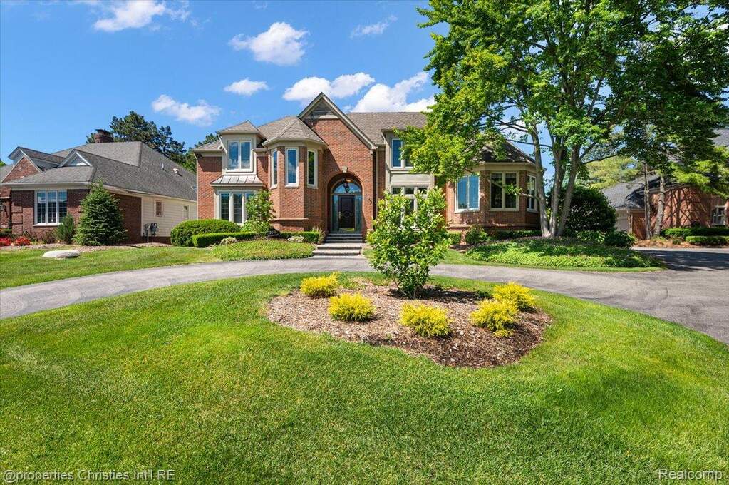 Brick facade residence featuring a grand arched entry, multiple bay windows, and a circular driveway