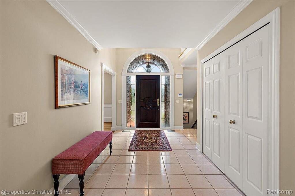 Foyer featuring a dark wood entry door with an arched transom, sidelights, and light-toned square tile flooring