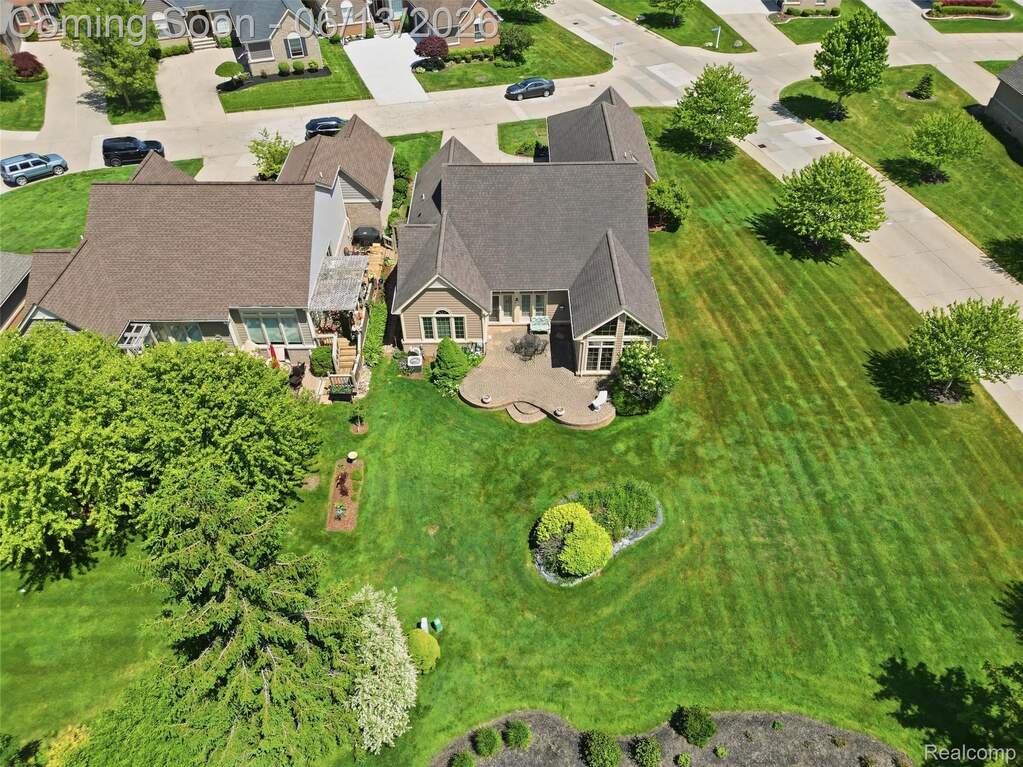 Large residential property featuring a sprawling green lawn, mature trees, and a multi-level stone patio