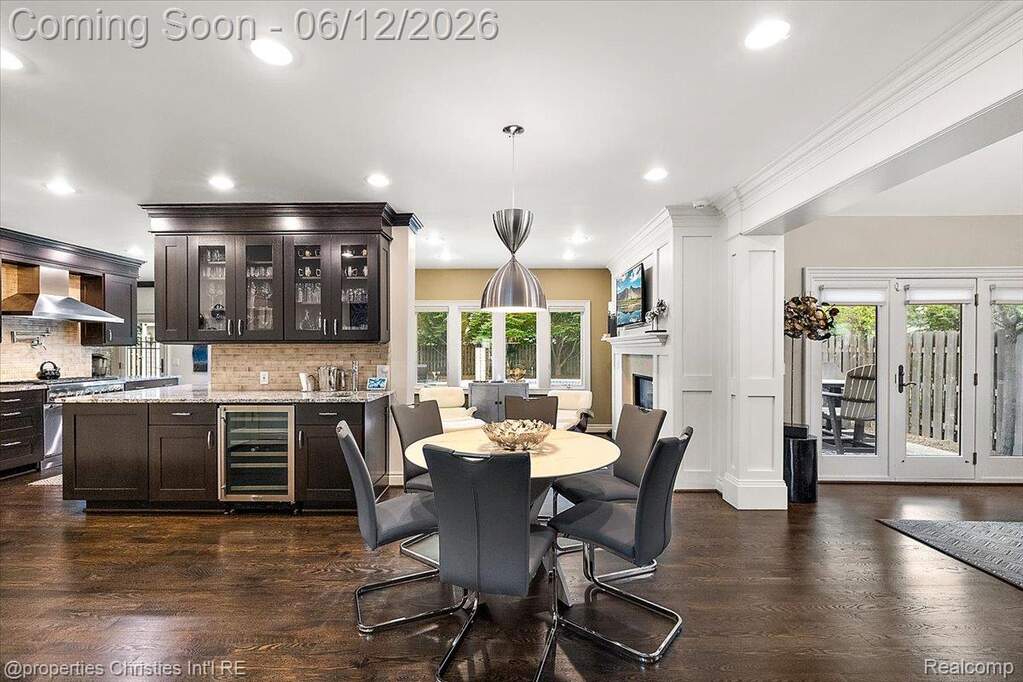 Open-concept kitchen and dining area featuring dark wood-finish flooring, recessed lighting, a built-in beverage refrigerator, and French patio doors leading to an exterior space