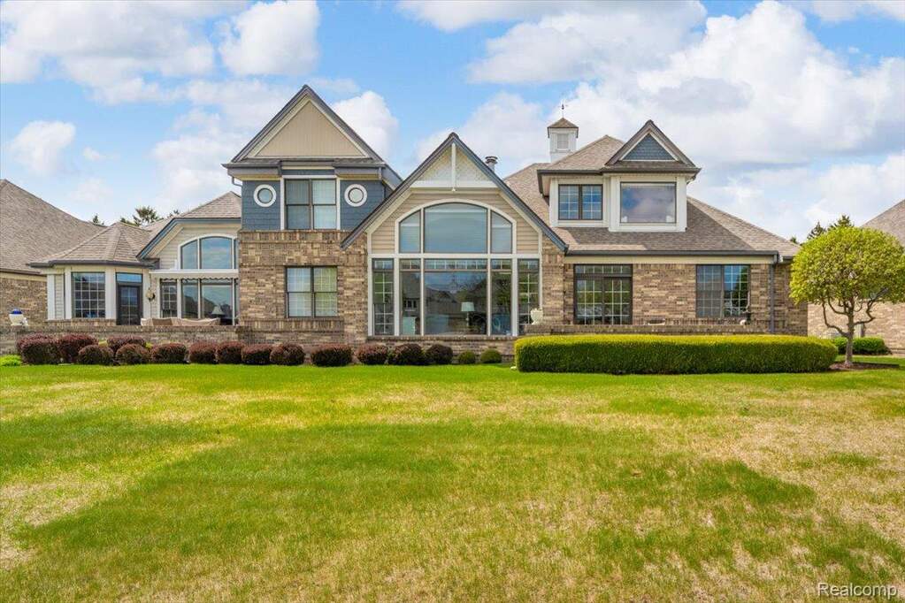 Stately residence featuring a brick and siding exterior, multiple gables, and large arched windows