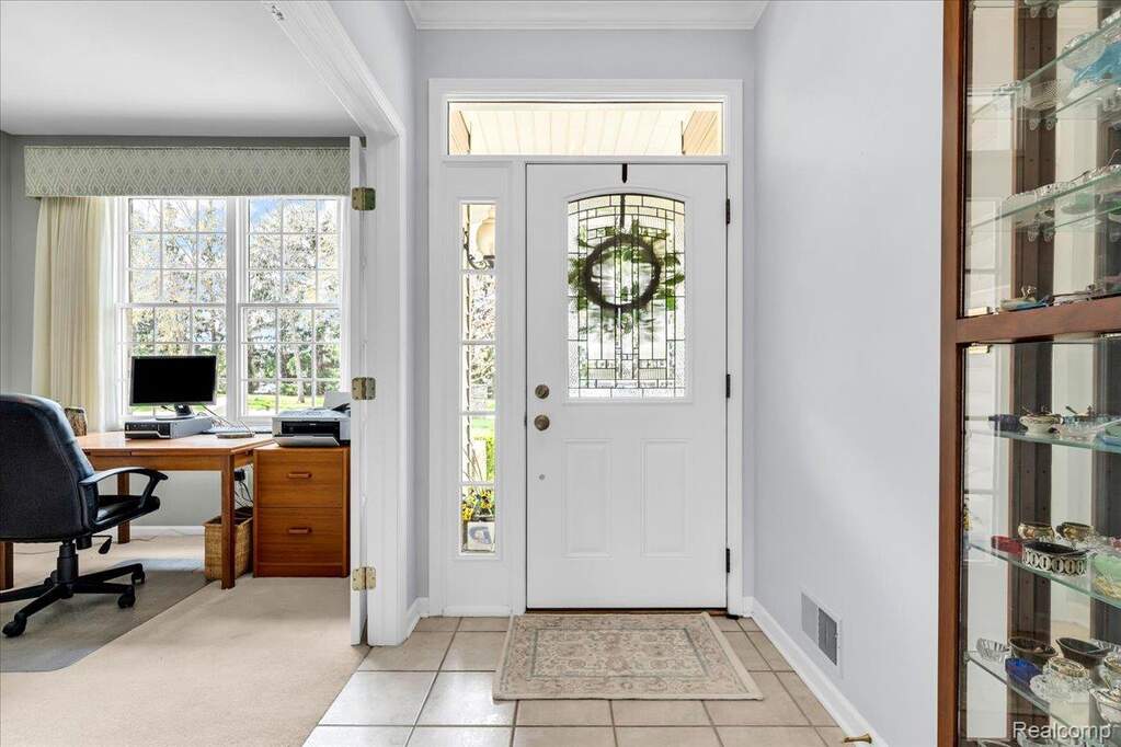 Entryway with a white paneled door featuring decorative leaded glass, flanked by sidelights and topped with a transom window