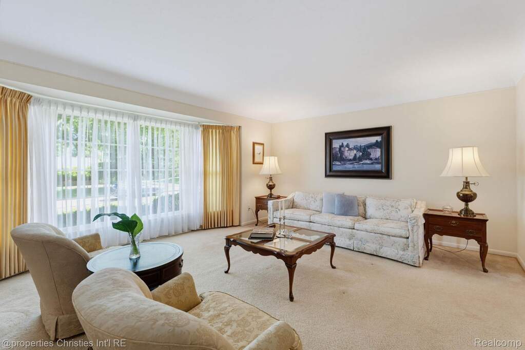 Bright living space featuring a large bay window, neutral wall paint, and plush carpeting