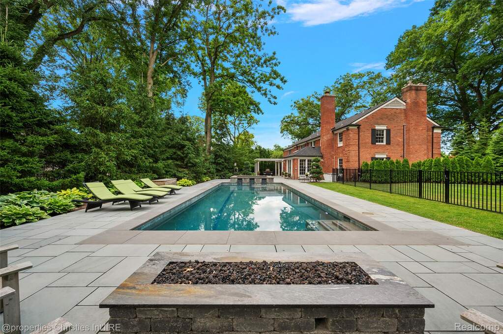 Rectangular in-ground swimming pool surrounded by a stone paver patio