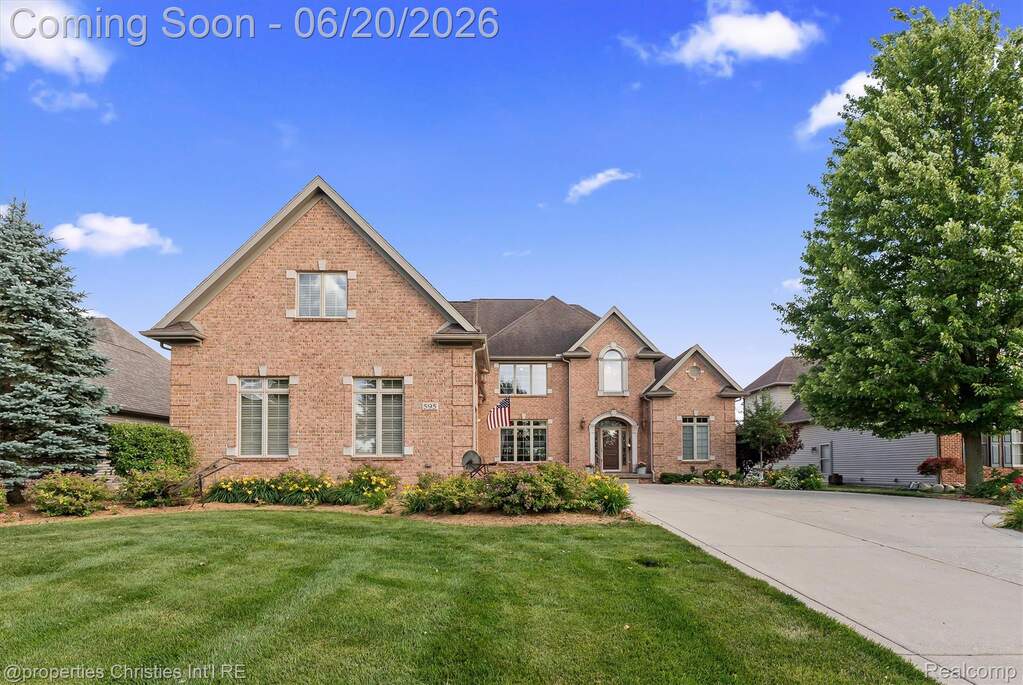 Brick two-story residence featuring a gabled roofline, arched entry, and decorative window headers