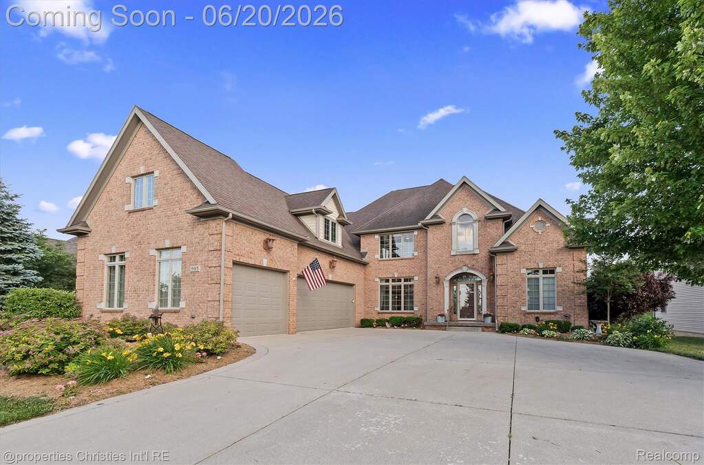 Brick-clad residence featuring a multi-gable roofline, arched entry, and prominent bay window