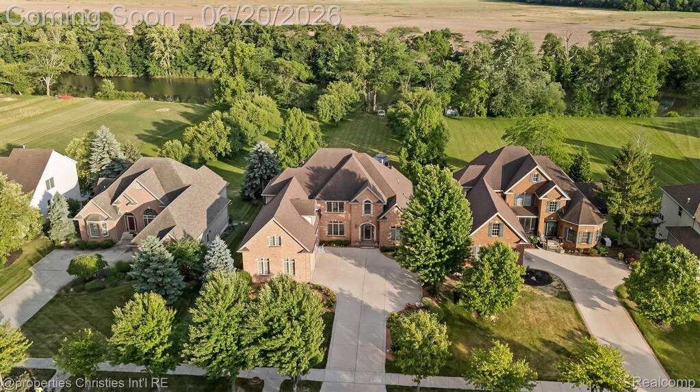 Brick exterior residence featuring a multi-gabled roofline, mature landscaping, and an expansive paved driveway