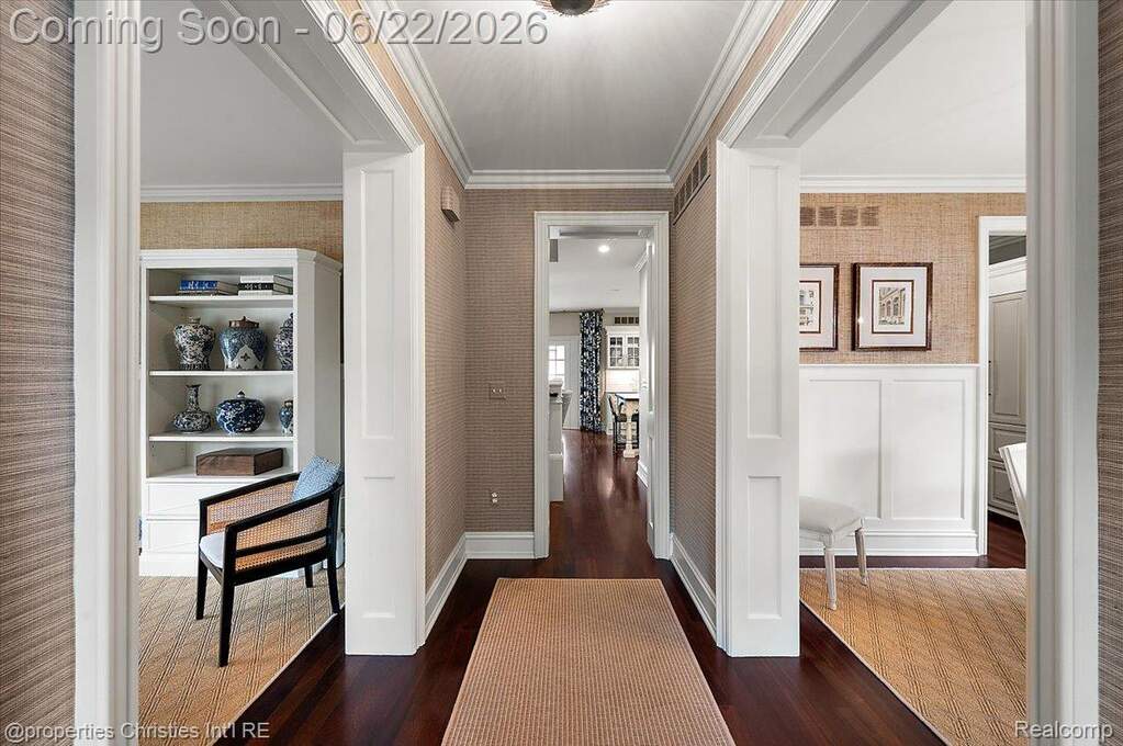 Hallway featuring dark wood-finish flooring, textured wallpaper, and crown molding