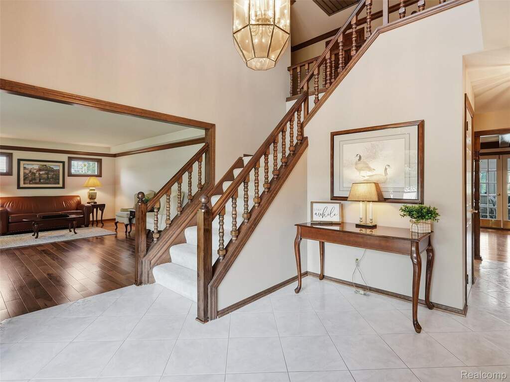 Two-story foyer featuring a grand staircase with wood banister and white carpeted treads