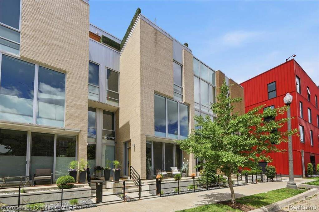 Modern townhome facade featuring light-colored brick and extensive fenestration