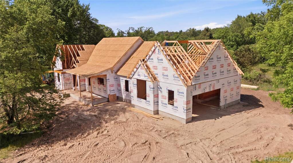 New construction framing featuring a multi-gable roof design, exposed porch framing, and an integrated two-car garage opening