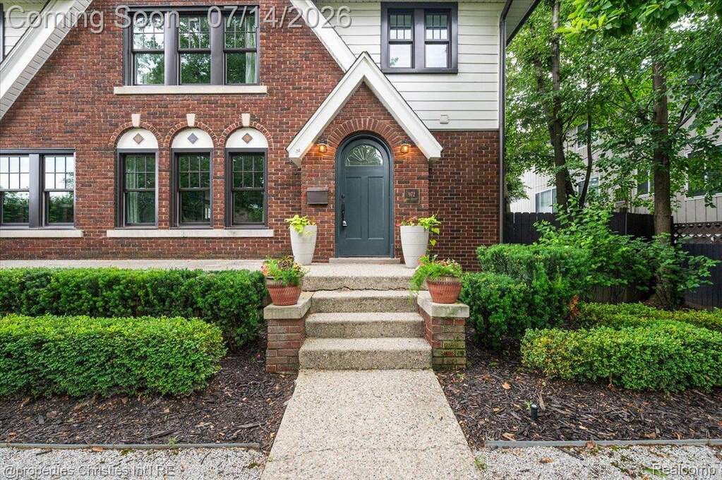 Brick facade with white siding accents and a dark arched entry door