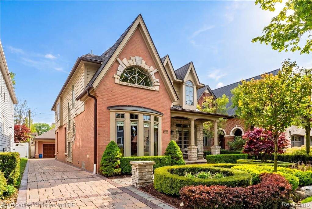View of front of home featuring brick siding, a porch, and a garage