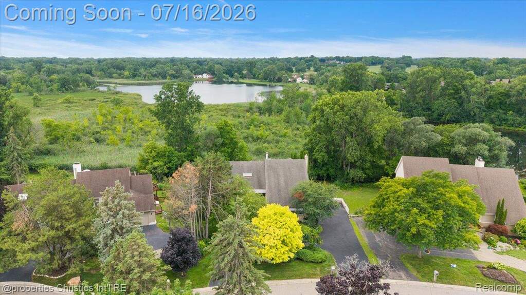 Aerial view of multiple properties featuring lush green landscaping, mature trees, and paved driveways