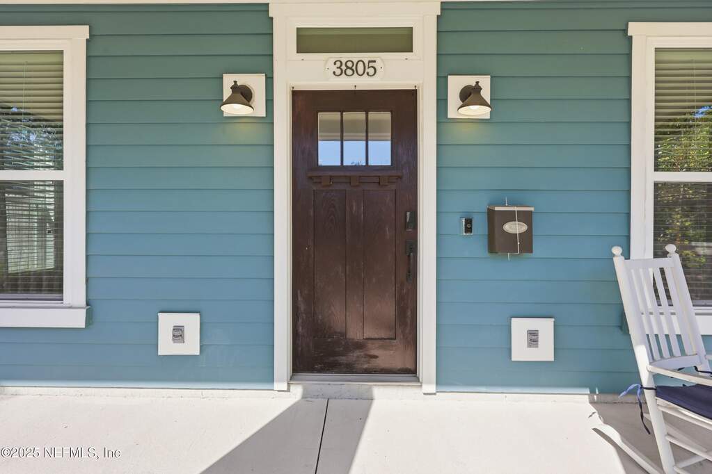 Front Exterior – Charming two-story home with a covered front porch, distinctive tapered columns, and classic blue siding complemented by white accents and landscaped hedges.