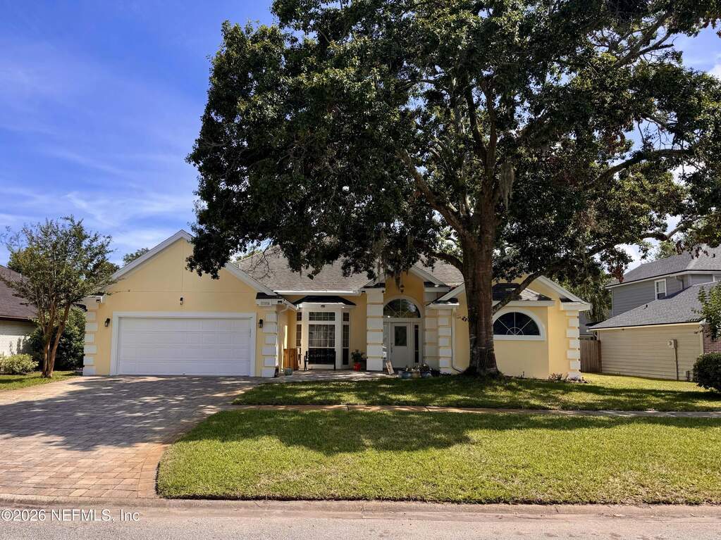 Sunny yellow stucco, paved driveway and front patio.