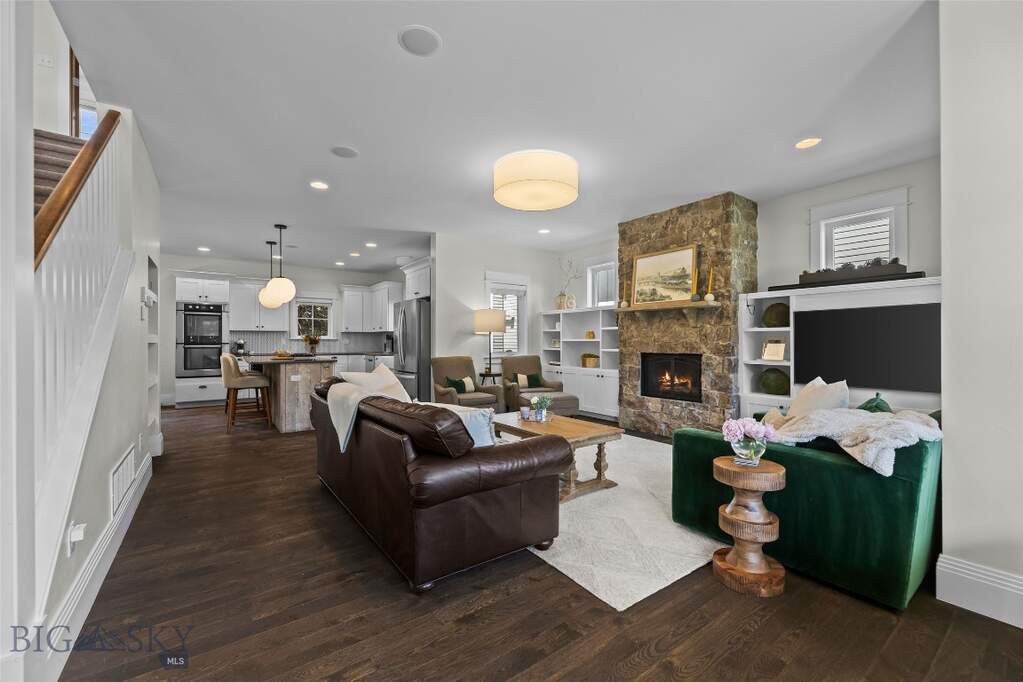 Living room with rich hardwood floors and stone fi