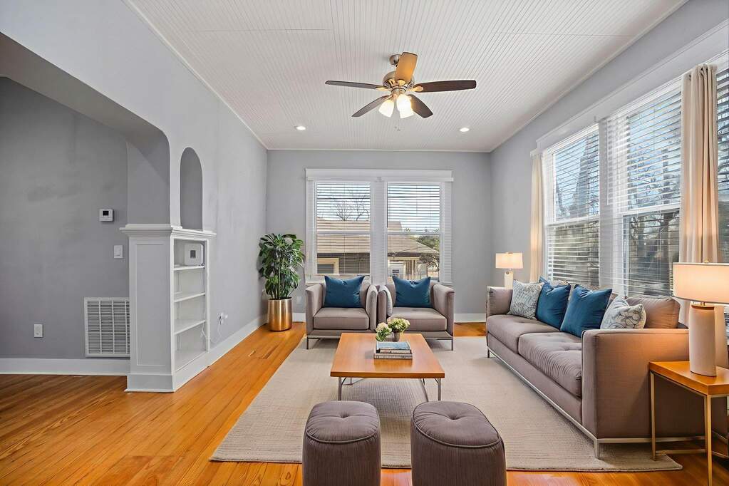 Living room featuring light wood finished floors, crown molding, ceiling fan, and arched walkways