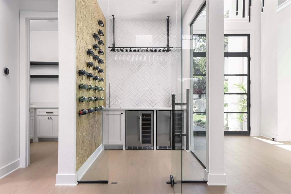 Dedicated beverage preparation area featuring a built-in wine rack, stemware holder, and two integrated beverage refrigerators
