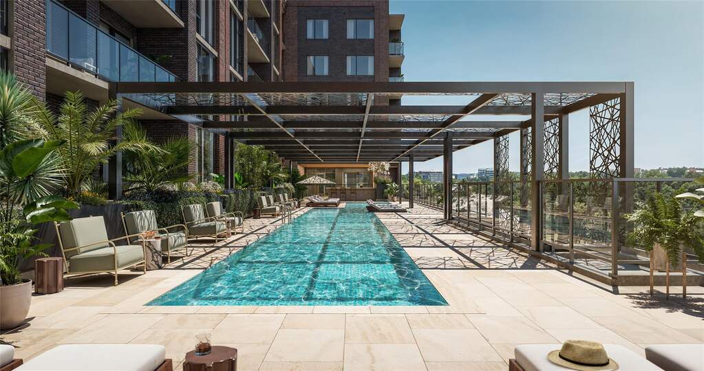 Resort-style pool deck featuring a 75-foot lap pool, tanning ledge, and shaded lounge areas. Designed for both relaxation and recreation, the pool is located adjacent to the resident lounge a
