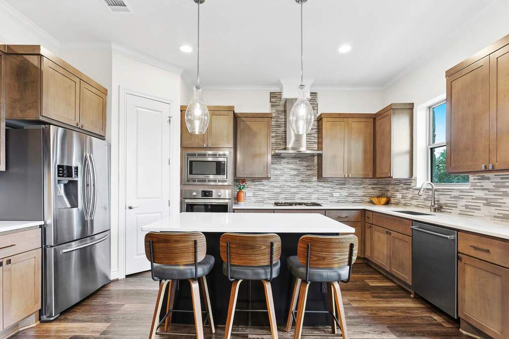 Kitchen with stainless steel appliances, decorative light fixtures, a breakfast bar area, ornamental molding, and a kitchen island