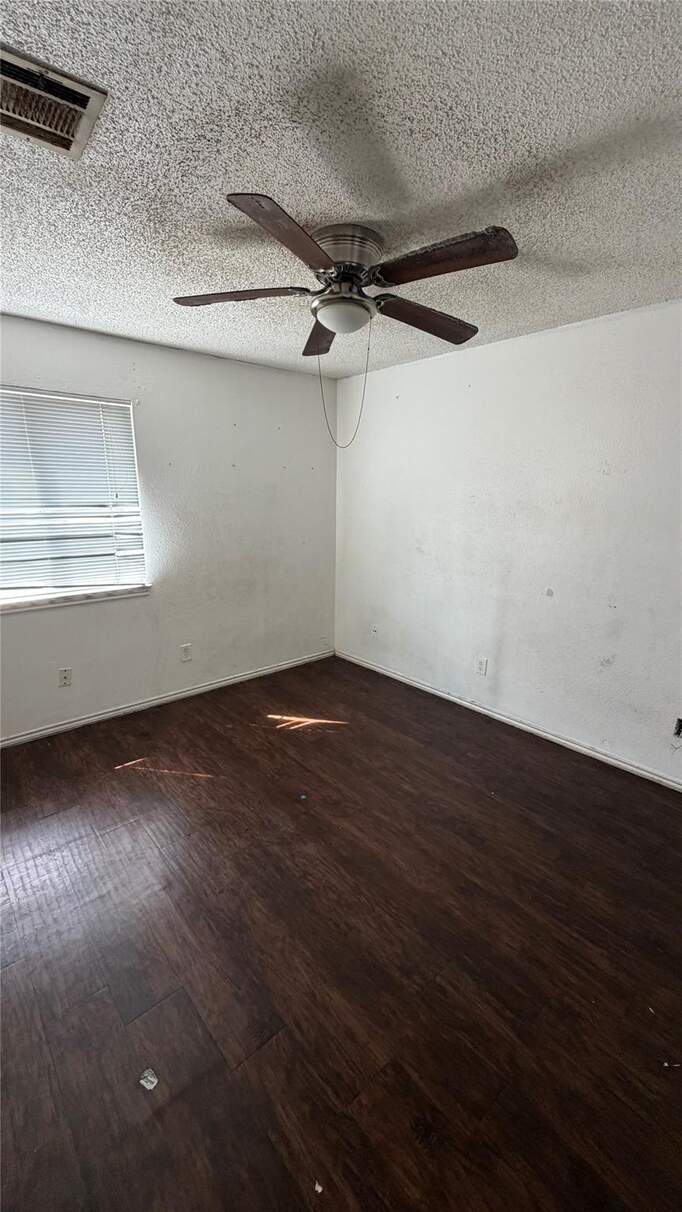 Spare room featuring dark wood-style floors, ceiling fan, and a textured ceiling
