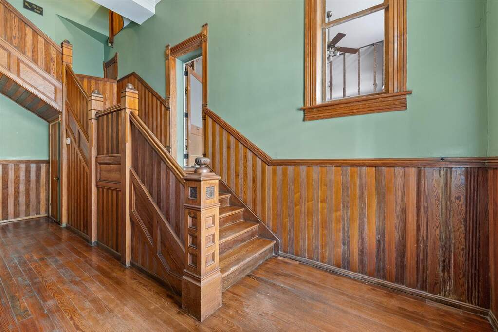 Staircase featuring wainscoting, wood walls, and hardwood / wood-style flooring