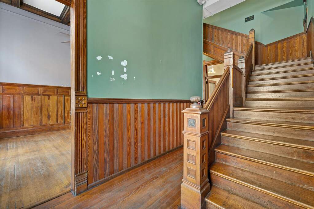 Staircase with a wainscoted wall, wood walls, and hardwood / wood-style flooring