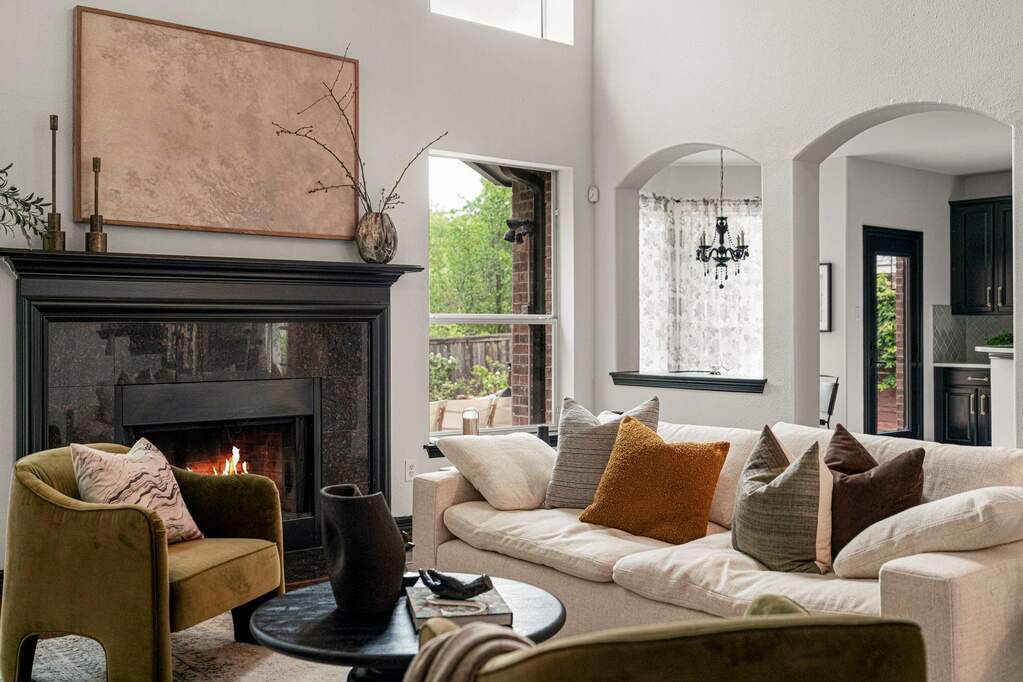 A striking fireplace with a dark mantel anchors this spacious, light-filled living area.